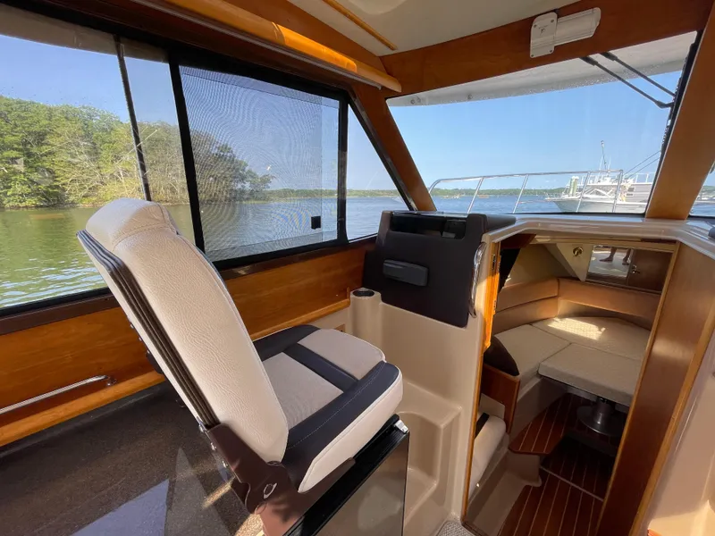 Slide: The Image of 2017 Cutwater C-28 boat interior with helm seat, cabin view, and scenic water backdrop. - 14