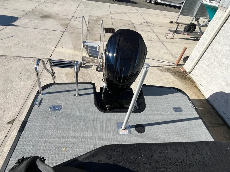 Slide: The Image of 2025 Starcraft EXS-3 boat with outboard motor and swim platform, parked on concrete. - 8