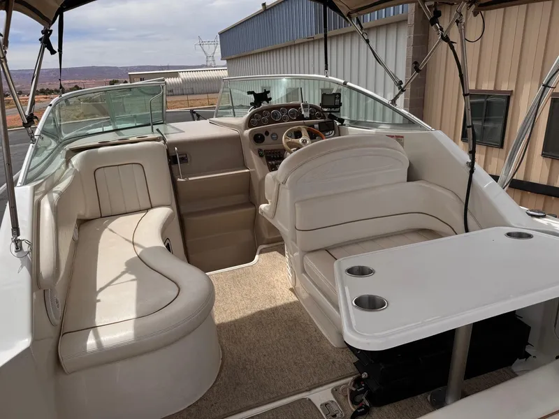Slide: The Image of 2001 Sea Ray 270 Sundancer boat interior with seating and helm, docked near buildings. - 18