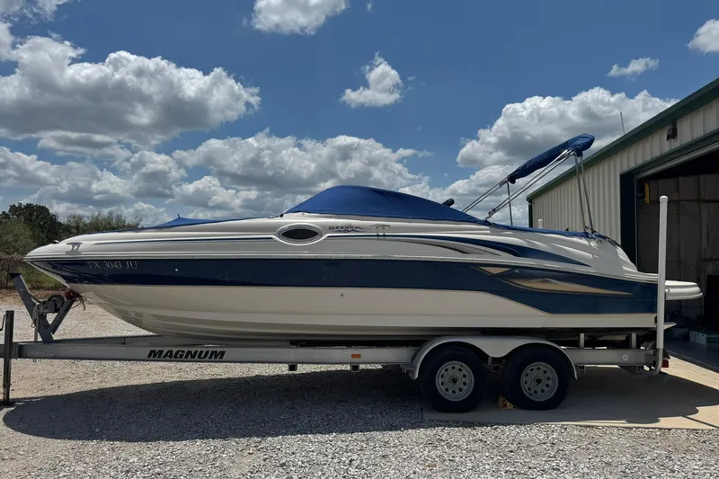 The Image of 2002 Sea Ray 240 Sundeck boat on trailer under a partly cloudy sky. - 0