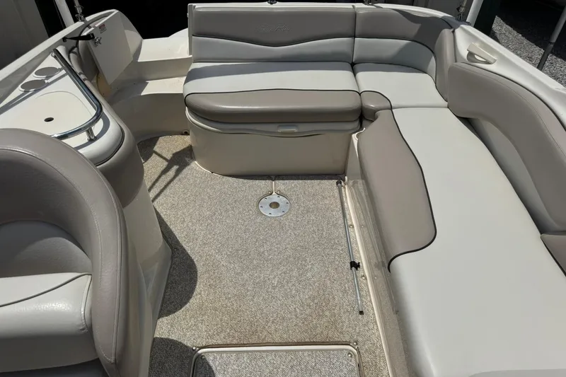 Slide: The Image of 2002 Sea Ray 240 Sundeck interior with beige seating and carpeted floor. - 15