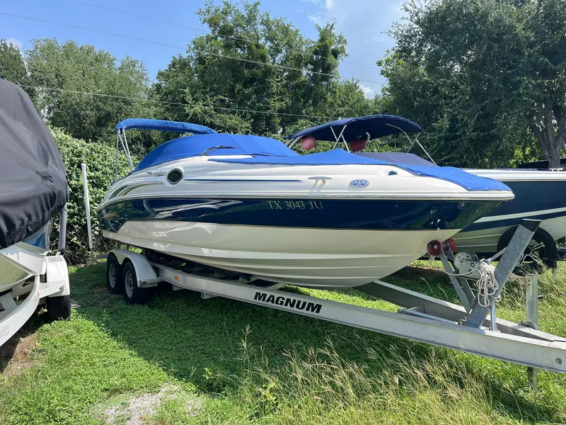 Slide: The Image of 2002 Sea Ray 240 Sundeck boat on trailer, blue and white, parked on grass. - 3