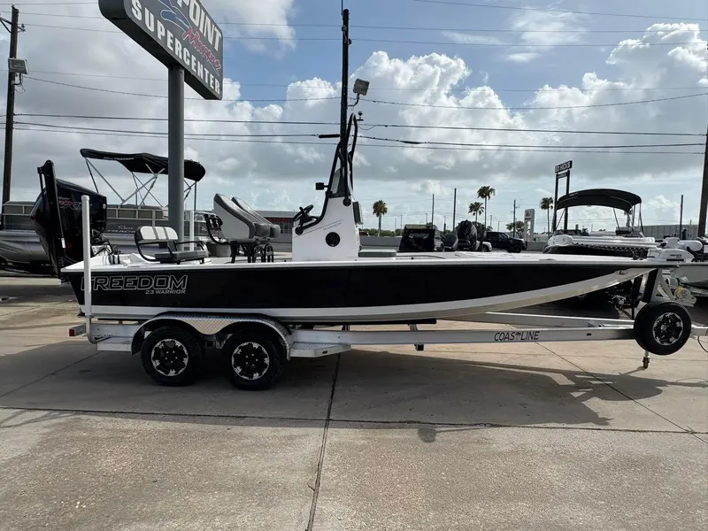 Slide: The Image of 2026 Freedom Boats USA 23' Warrior on trailer at dealership under cloudy sky. - 2