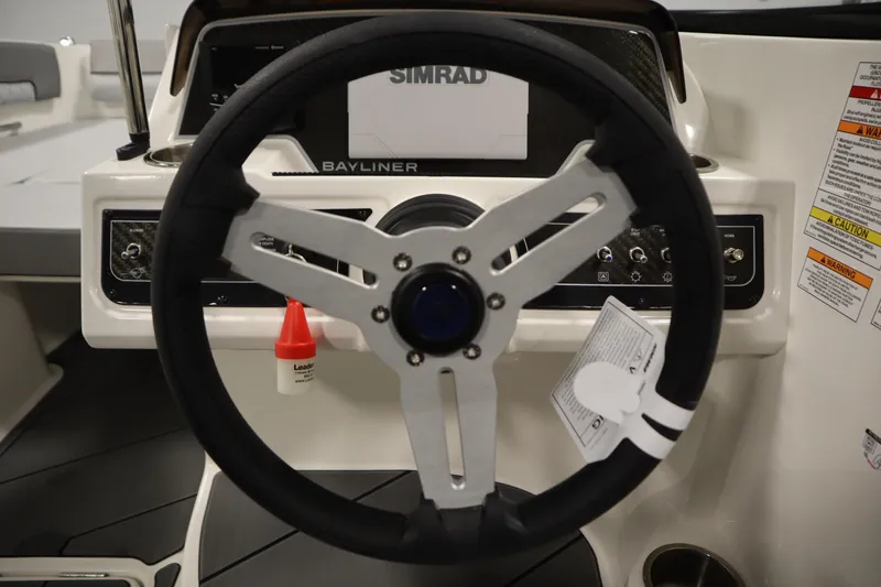 Slide: The Image of Steering wheel of 2025 Bayliner D22I boat with control panel and Simrad display. - 12
