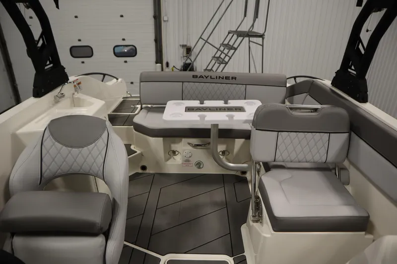 Slide: The Image of 2025 Bayliner D22I boat interior with gray seating and table in a showroom. - 25