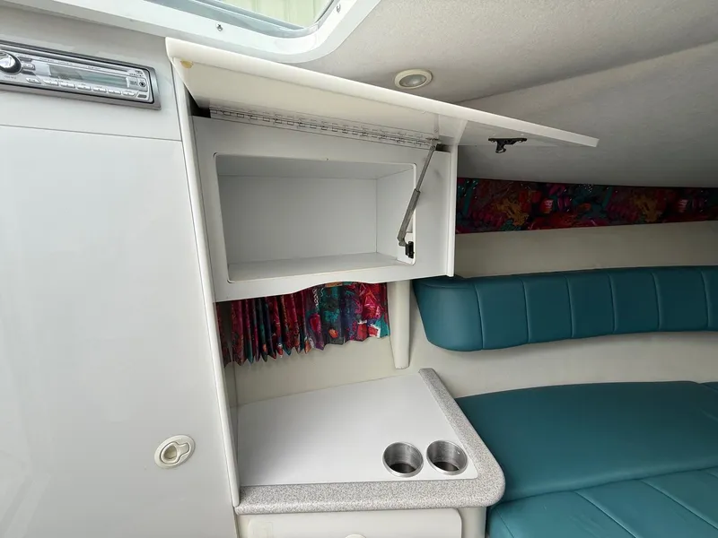 Slide: The Image of 1997 Formula 280SS boat interior with open cabinet, teal seating, and colorful curtains. - 15