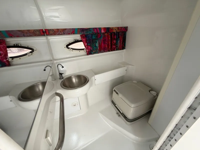 Slide: The Image of 1997 Formula 280SS boat bathroom with sink, toilet, and colorful curtains. - 16