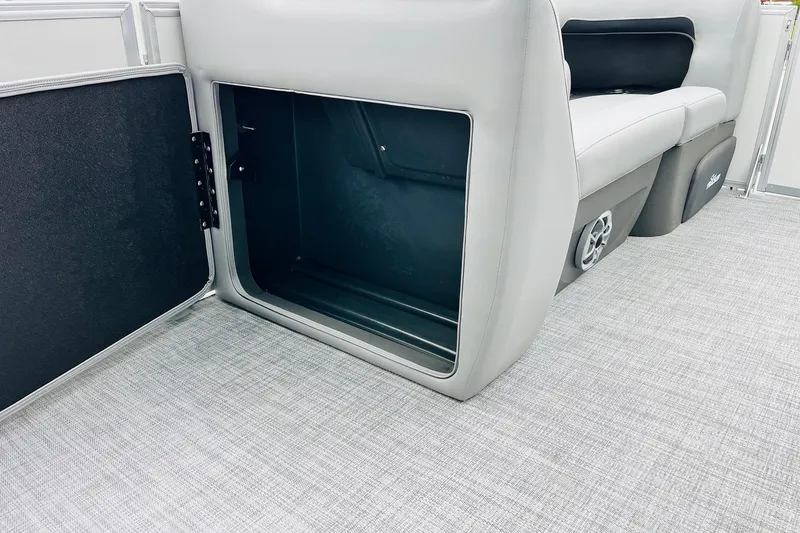 Slide: The Image of 2026 Sun Tracker Party Barge 22 DLX storage compartment with open door, gray interior. - 18