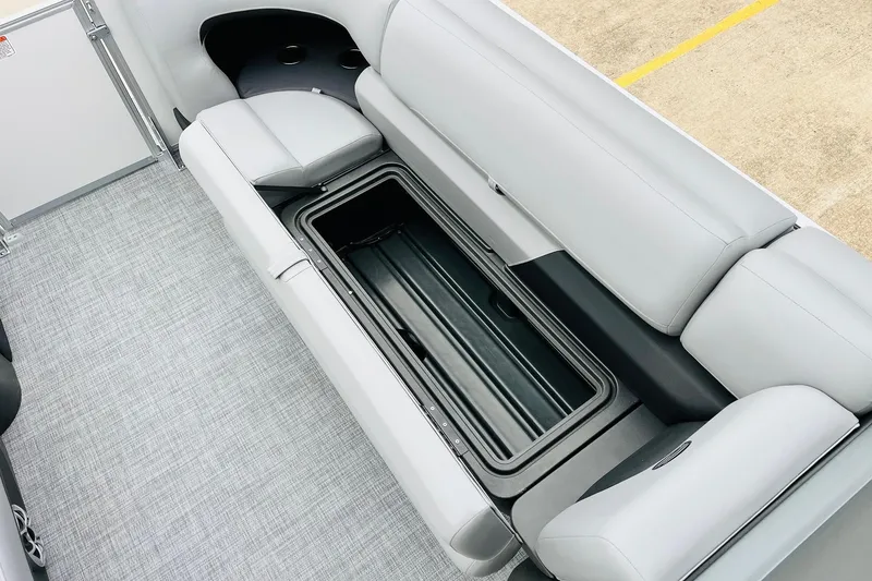 Slide: The Image of 2026 Sun Tracker Party Barge 22 DLX with open storage compartment and gray seating. - 25