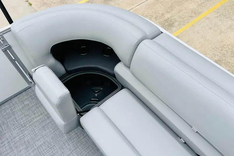 Slide: The Image of 2026 Sun Tracker Party Barge 22 DLX, gray seating with storage compartment, outdoor setting. - 27