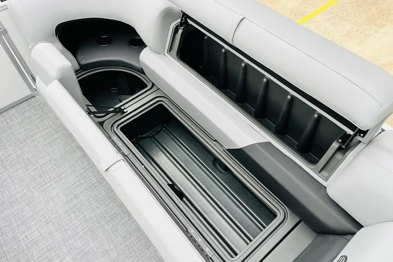 Slide: The Image of 2026 Sun Tracker Party Barge 22 DLX with open storage compartments and gray seating. - 28