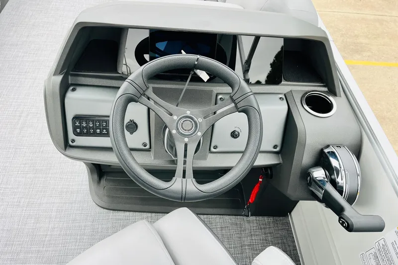 Slide: The Image of Steering console of 2026 Sun Tracker Party Barge 22 DLX with modern controls and cup holder. - 32