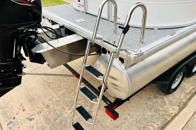 Slide: The Image of 2026 Sun Tracker Party Barge 22 DLX with motor and boarding ladder on trailer. - 9