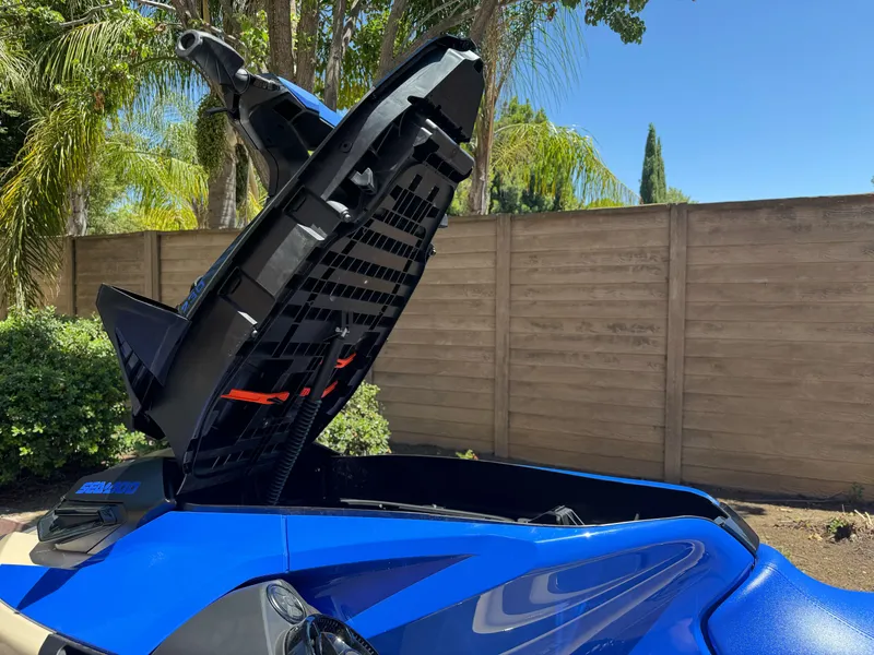 Slide: The Image of 2025 Sea-Doo Wake Pro 230 with open storage compartment, blue exterior, outdoor setting. - 10