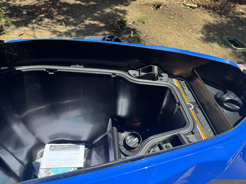 Slide: The Image of Open storage compartment of 2025 Sea-Doo Wake Pro 230, showing interior details and manual. - 11
