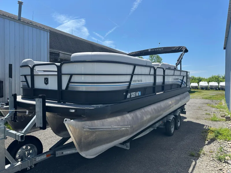 The Image of 2022 Godfrey SWEETWATER 2286 SFL pontoon boat on trailer, parked outdoors. - 0