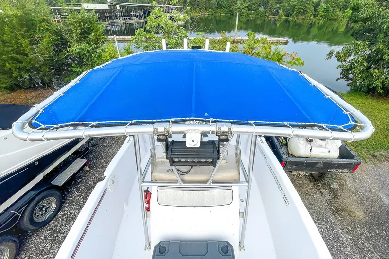 Slide: The Image of 2000 Pro-Line 20 Sport boat with blue canopy, parked near a lake. - 16