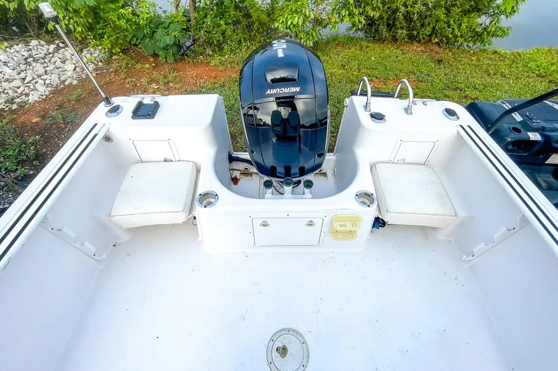 Slide: The Image of 2000 Pro-Line 20 Sport boat interior with Mercury engine, white seating, and lush greenery background. - 18
