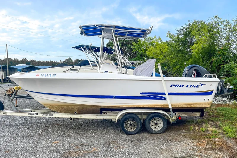 Slide: The Image of 2000 Pro-Line 20 Sport boat on trailer, parked outdoors with trees in background. - 2