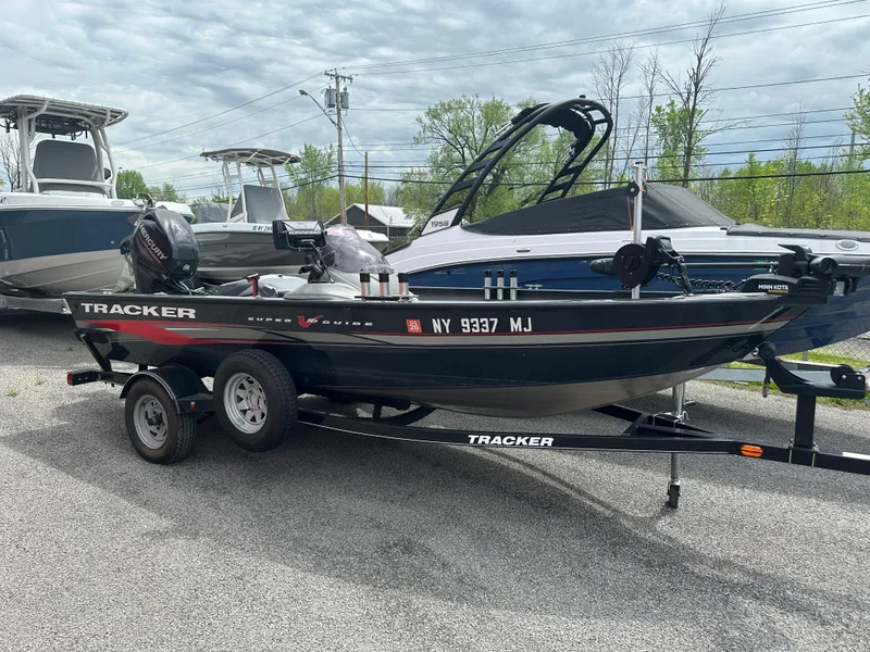 The Image of 2013 Tracker Super Guide V-16 SC boat on trailer, parked outdoors. - 0