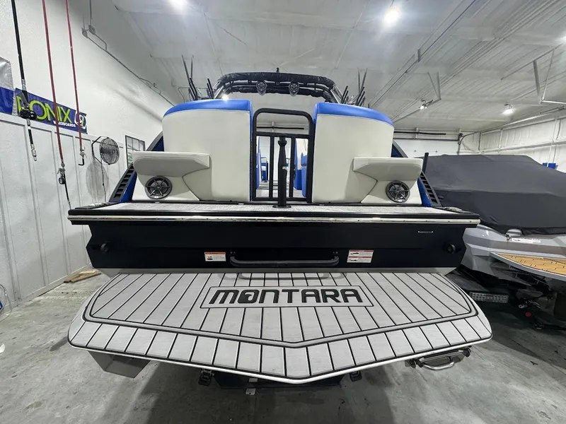 Slide: The Image of 2025 Montara Surf Boss boat in showroom, blue and white design on trailer. - 2