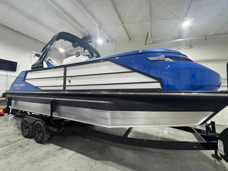 Slide: The Image of 2025 Montara Surf Boss boat on trailer in showroom, blue and white design. - 5