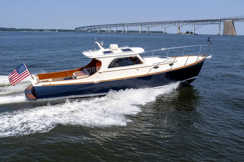Slide: The Image of 2007 Hinckley Picnic Boat EP cruising on water near a bridge, American flag displayed. - 0