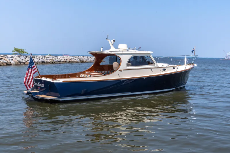 Slide: The Image of 2007 Hinckley Picnic Boat EP on calm water, featuring classic design and American flag. - 12