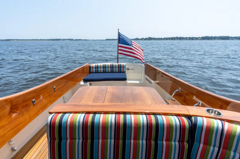 Slide: The Image of 2007 Hinckley Picnic Boat EP with striped seating, American flag, on open water. - 16