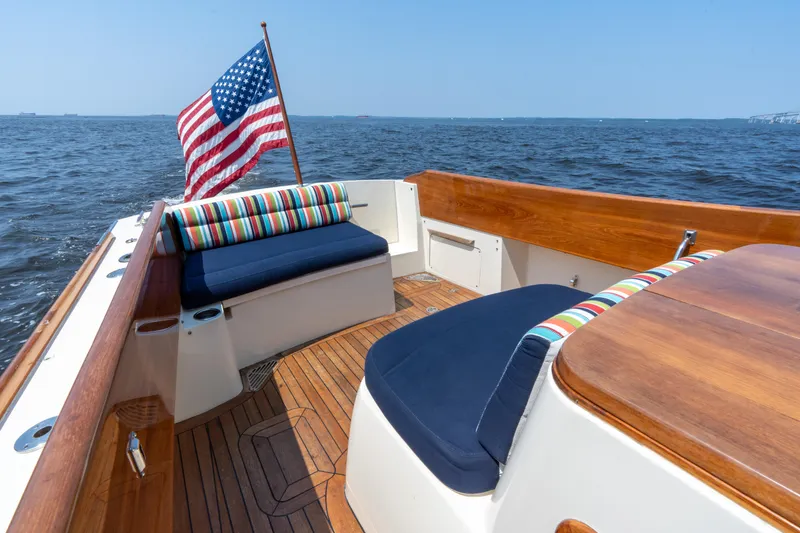 Slide: The Image of 2007 Hinckley Picnic Boat EP with American flag, wooden deck, and colorful seating on open water. - 17