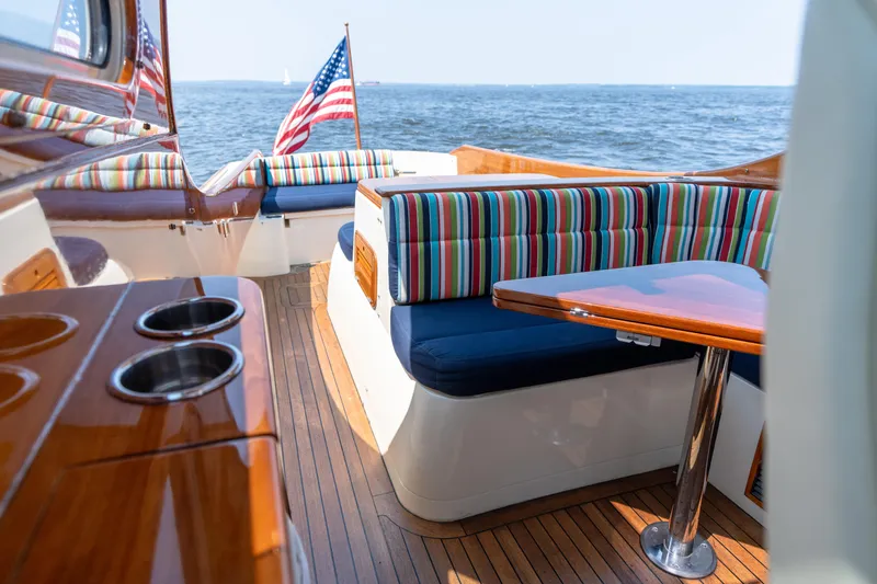 Slide: The Image of 2007 Hinckley Picnic Boat EP interior with striped seating, wooden table, and ocean view. - 29