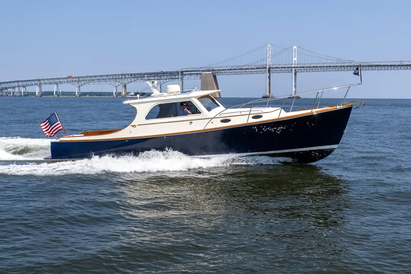 Slide: The Image of 2007 Hinckley Picnic Boat EP cruising on water near a bridge, American flag displayed. - 3