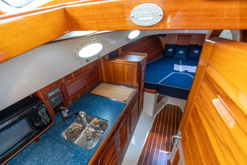 Slide: The Image of 2007 Hinckley Picnic Boat EP interior with wood finish, kitchenette, and cozy sleeping area. - 35