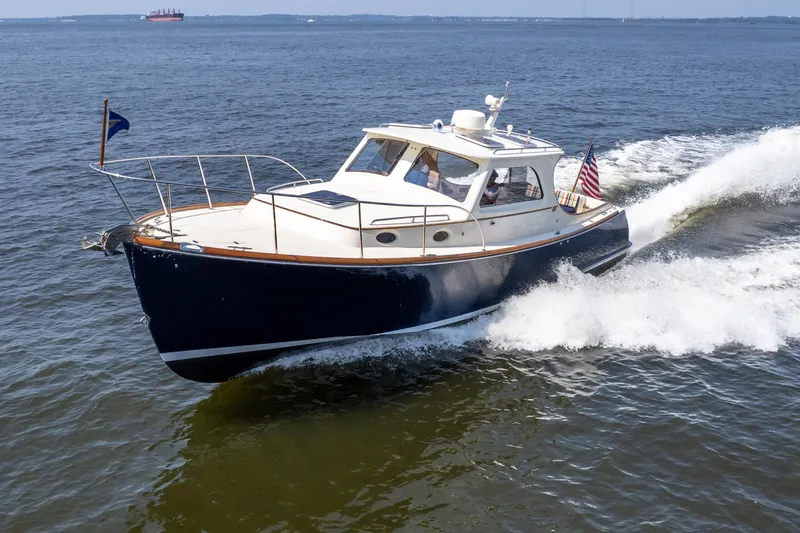 Slide: The Image of 2007 Hinckley Picnic Boat EP cruising on open water, displaying sleek design and American flag. - 6