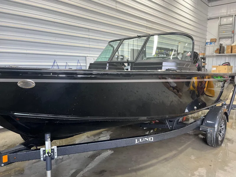 The Image of 2026 Lund 1800 Explorer Sport boat in a garage, sleek black exterior. - 1