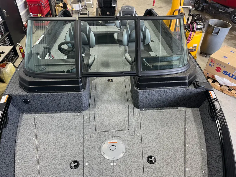 Slide: The Image of 2026 Lund 1800 Explorer Sport boat interior with dual seats and windshield in a garage setting. - 13