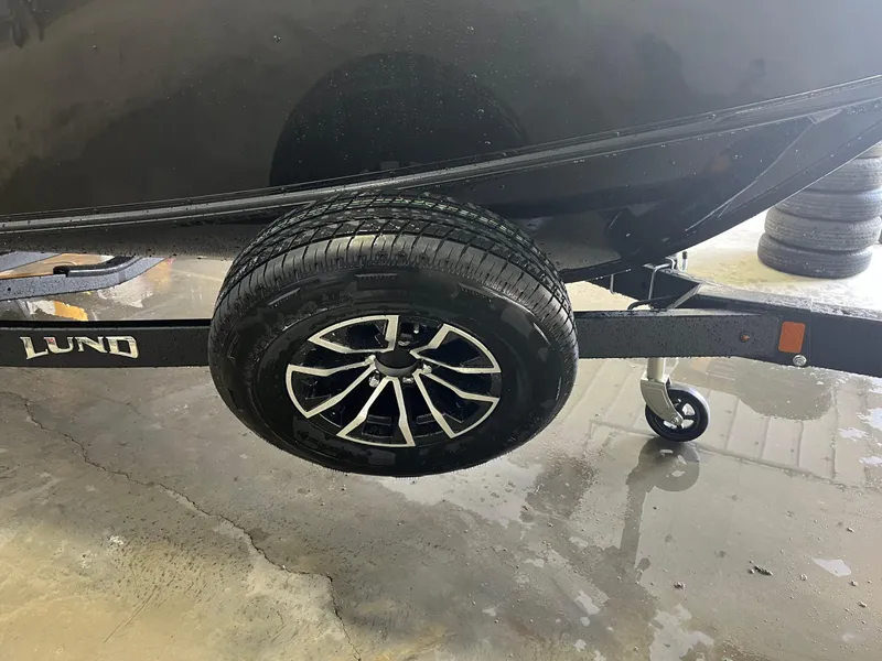 Slide: The Image of 2026 Lund 1800 Explorer Sport trailer wheel on wet concrete surface. - 4