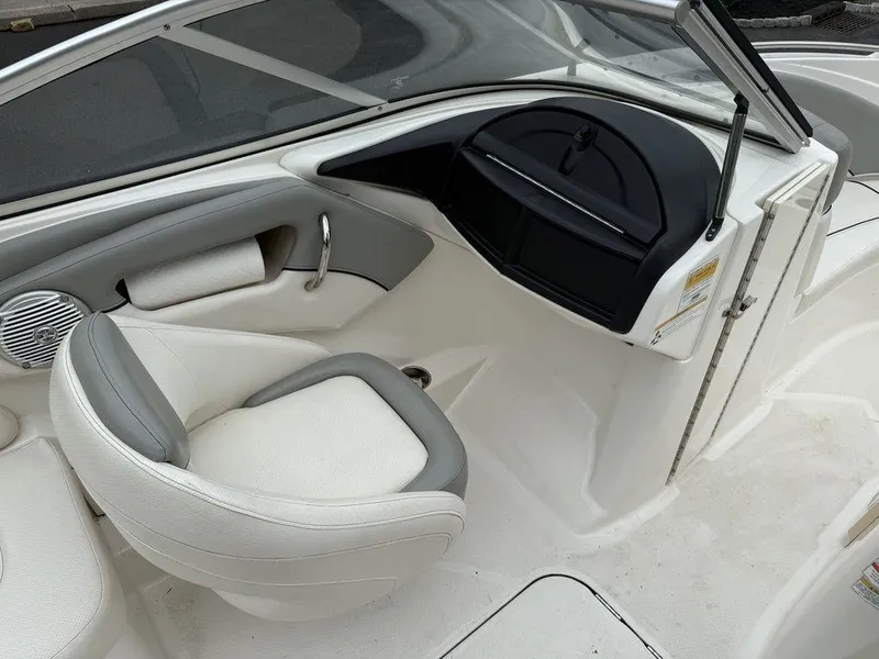 Slide: The Image of 2012 Bayliner 235 BR boat interior with white and gray seating and dashboard. - 14