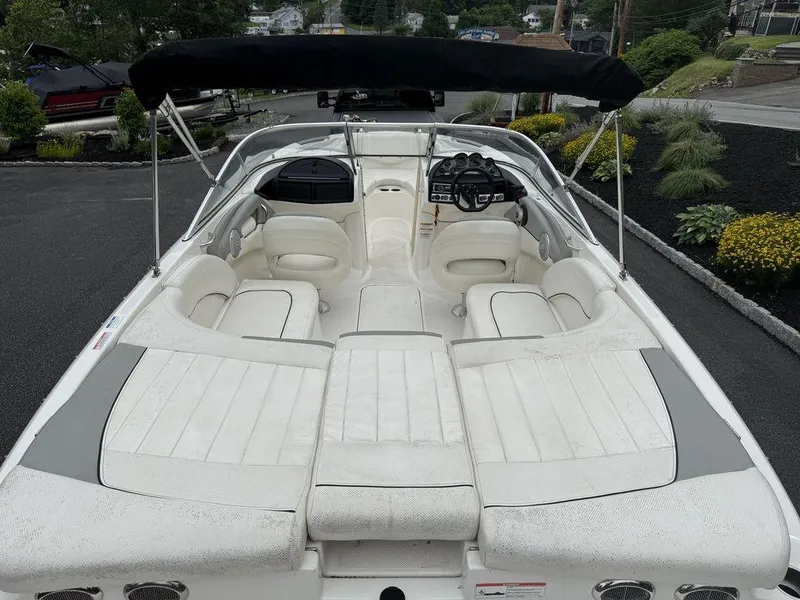 Slide: The Image of 2012 Bayliner 235 BR boat with white seating and black canopy, parked outdoors. - 5