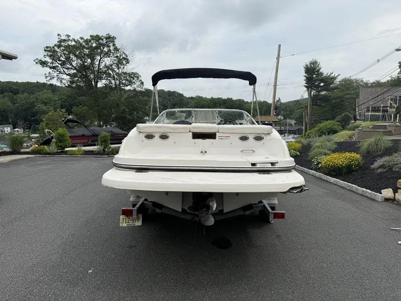 Slide: The Image of 2012 Bayliner 235 BR boat on trailer, parked outdoors with scenic background. - 9