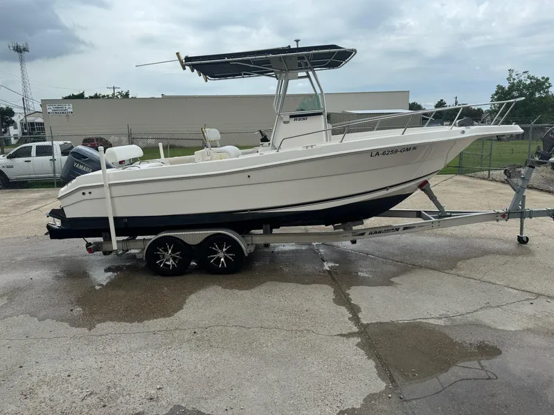 The Image of 2004 Robalo R230 Center Console boat on trailer, parked outdoors. - 0