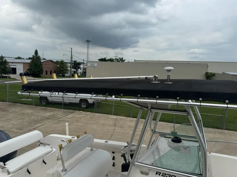Slide: The Image of 2004 Robalo R230 Center Console boat with T-top, parked outdoors under cloudy skies. - 10