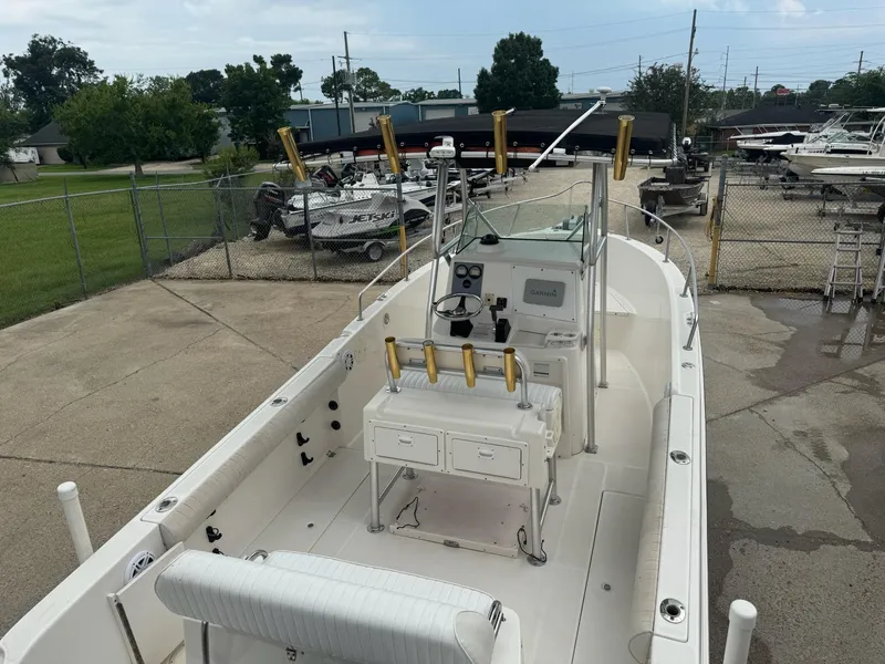 Slide: The Image of 2004 Robalo R230 Center Console boat in a marina, featuring a clean deck and fishing rod holders. - 11