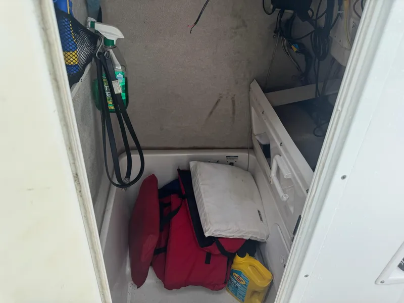 Slide: The Image of Storage compartment in a 2004 Robalo R230 Center Console boat with cleaning supplies and cushions. - 30