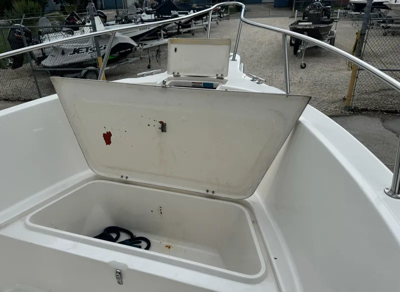 Slide: The Image of Open storage compartment on 2004 Robalo R230 Center Console boat, docked near other vessels. - 32