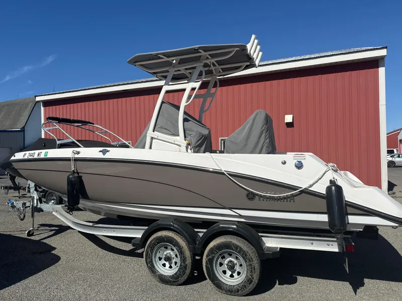 Slide: The Image of 2022 Yamaha Boats 210 FSH Sport on trailer, parked near red building. - 8