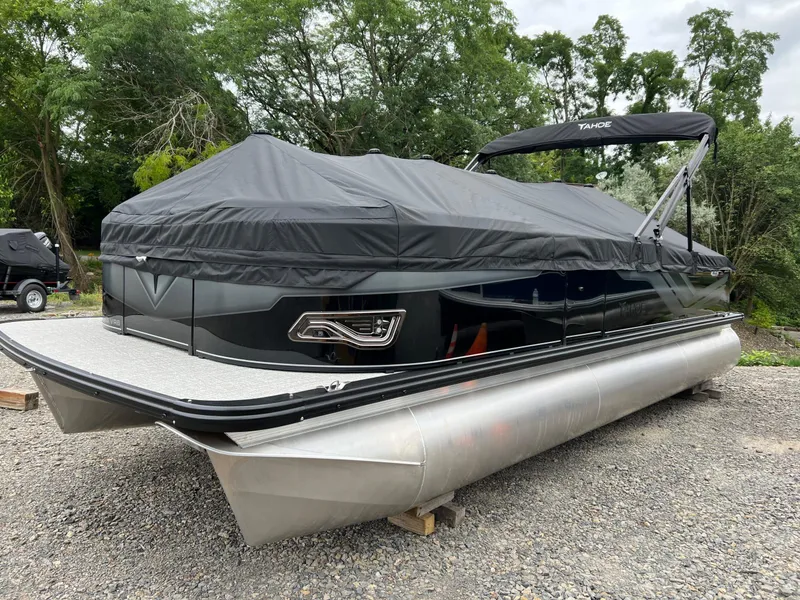 Slide: The Image of 2026 Tahoe Pontoon 2385 VRB with cover, parked on gravel, surrounded by trees. - 8