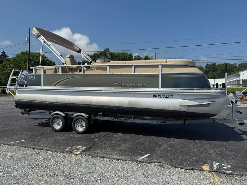Slide: The Image of 2009 Bennington 2275QXi pontoon boat on trailer, parked outdoors under clear sky. - 6