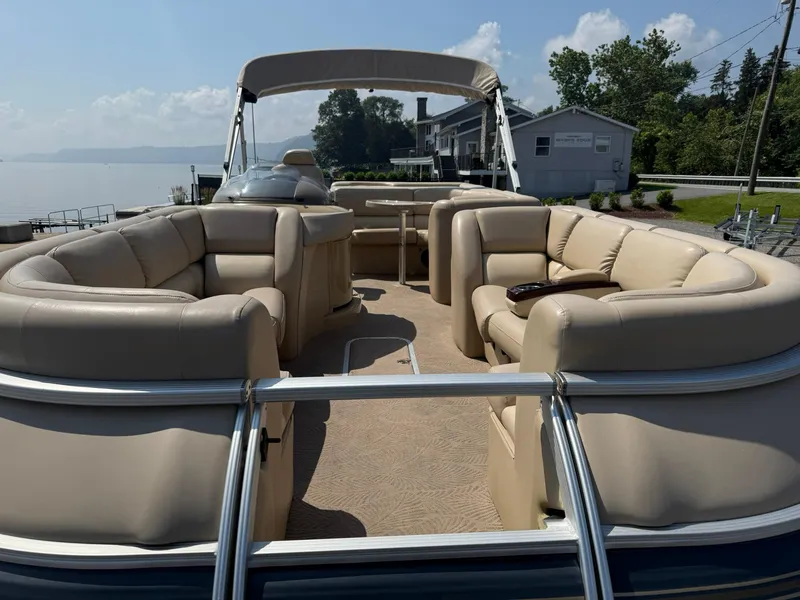 Slide: The Image of 2009 Bennington 2275QXi pontoon boat with beige seating, docked by a serene lake. - 7