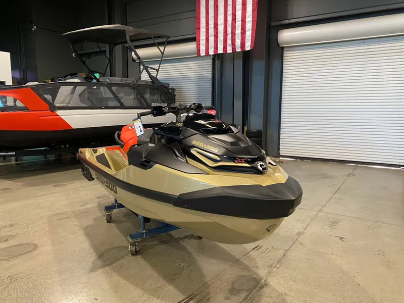 Slide: The Image of 2025 Sea-Doo RXT-X 325 jet ski in showroom, American flag backdrop. - 2